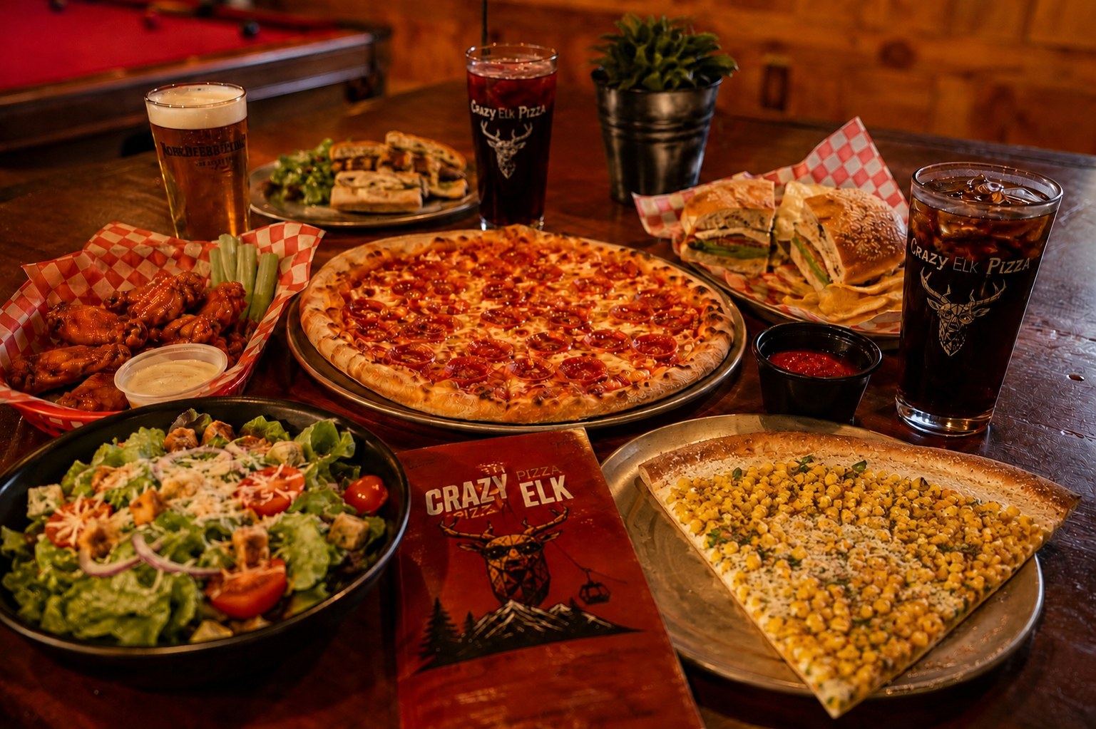 Spread of pizza, wings, salad, sandwiches, and drinks at Crazy Elk Pizza