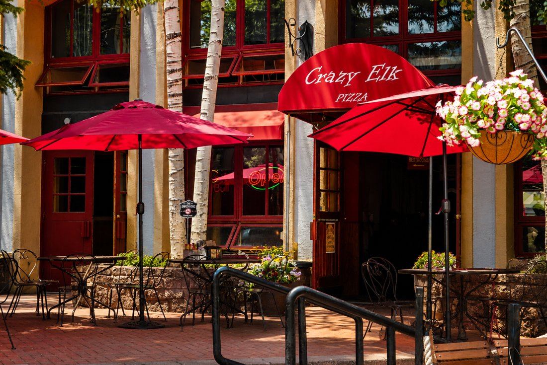 Crazy Elk Pizza storefront with red umbrellas